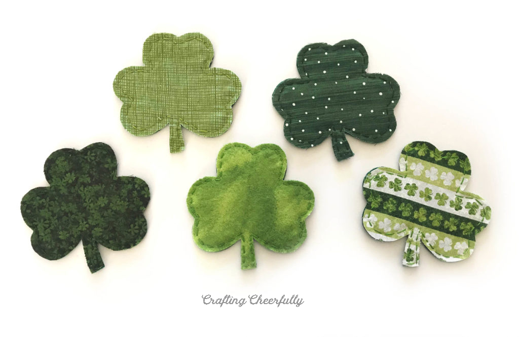 Five fabric shamrocks on a white background.