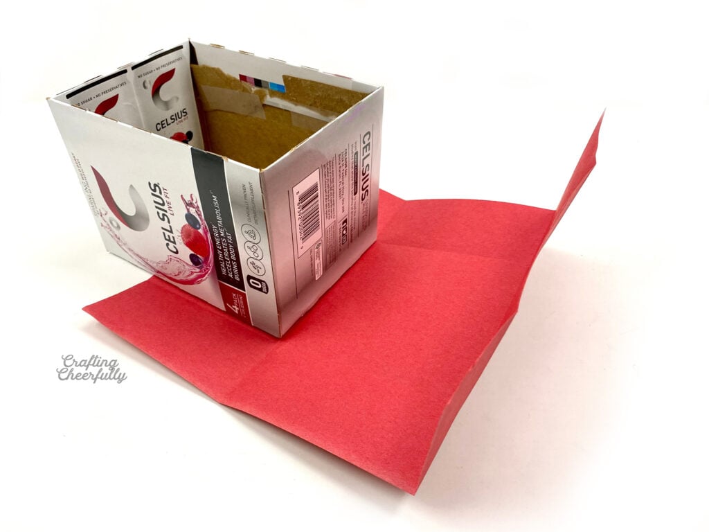 Red paper is pre-folded sitting next to a cardboard box.