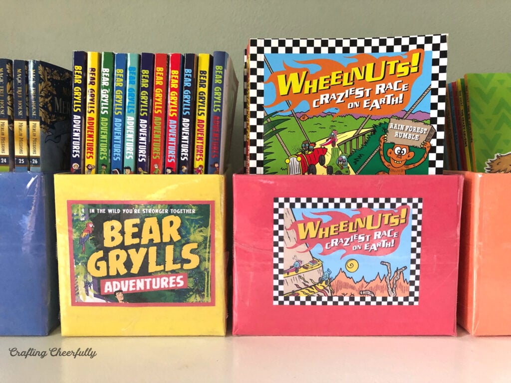 Colorful DIY book bins holding chapter books sit on a dresser. 