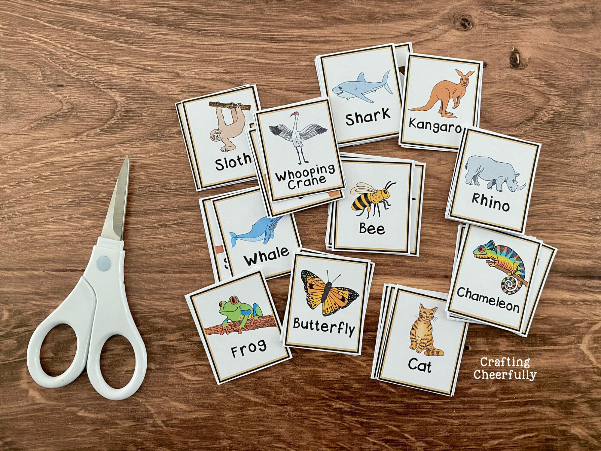 Calling cards for Animal BINGO lay on a table with a white scissors.