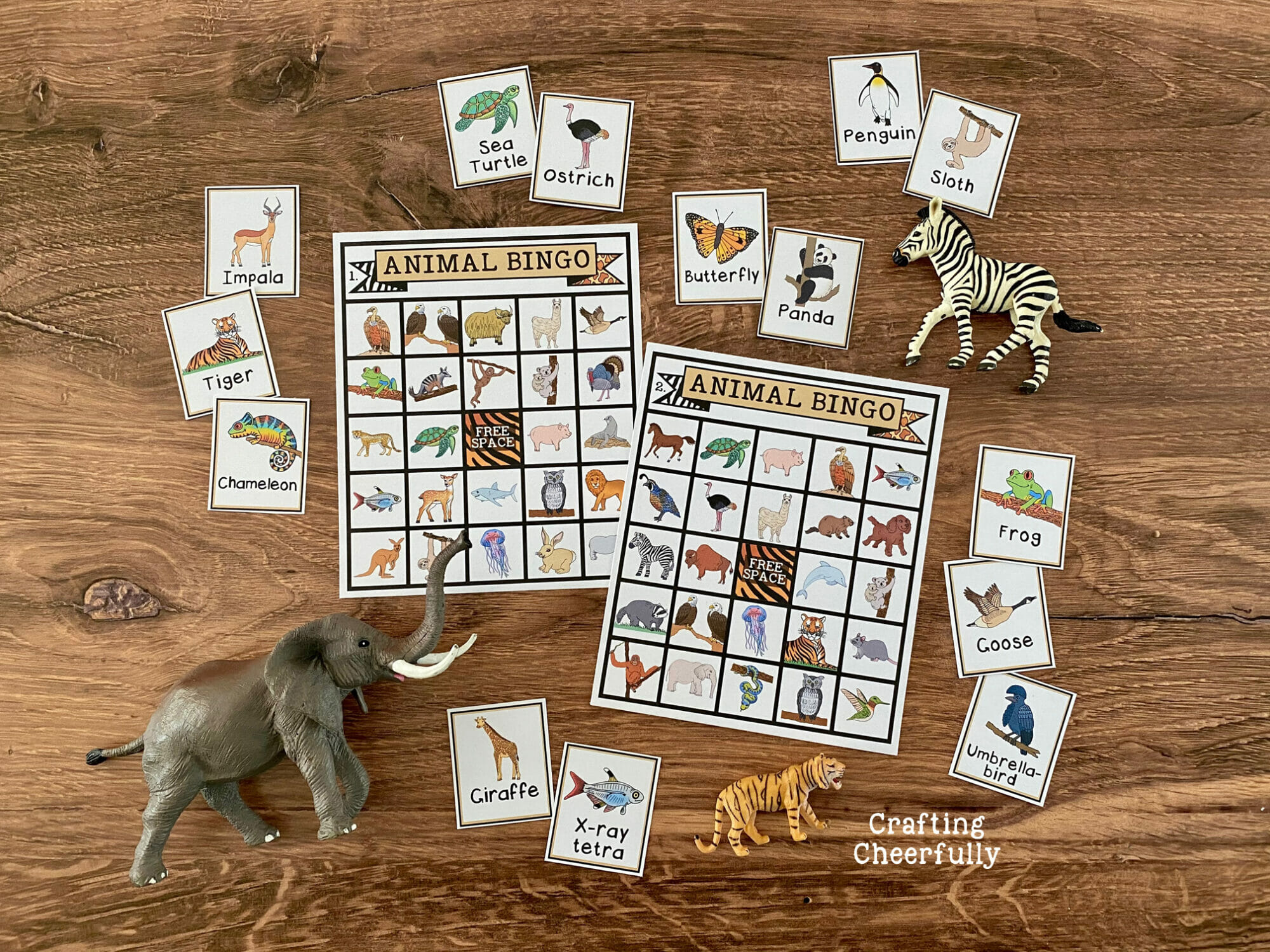 Animal BINGO boards on a wooden surface with calling cards and toy animals laying around them.