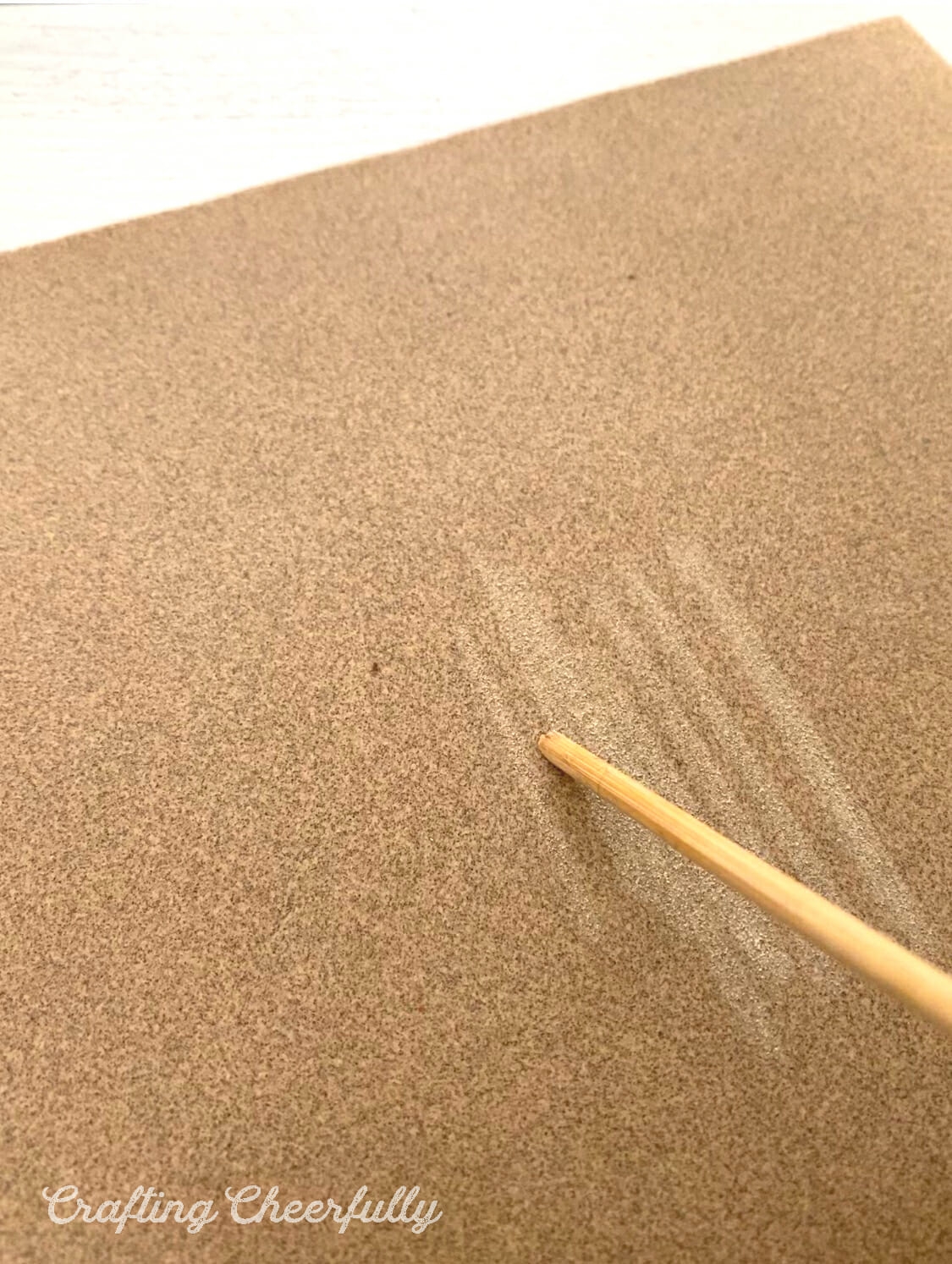 A dowel is rubbed against sand paper.