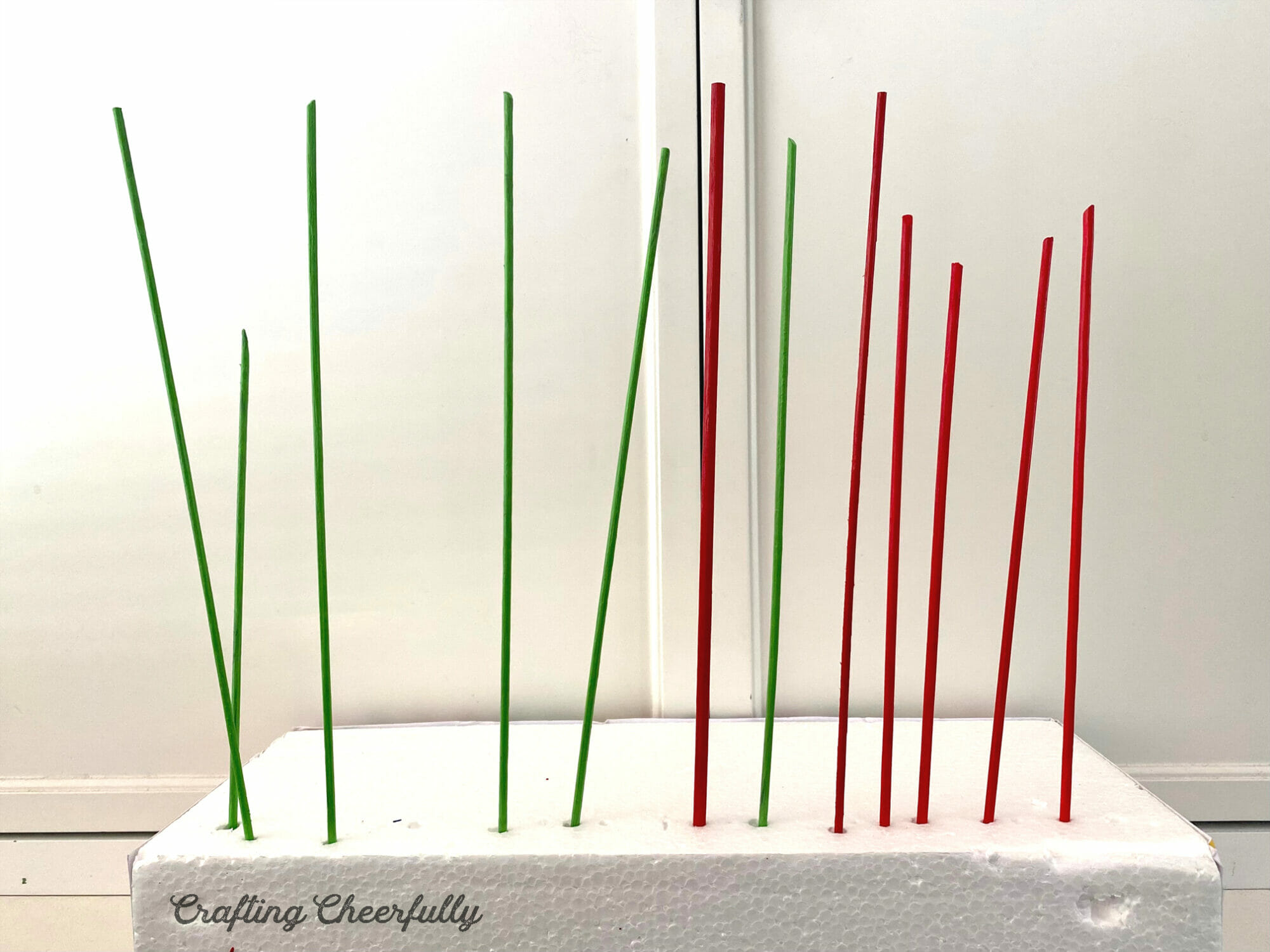 Painted dowels dry in a piece of styrofoam.