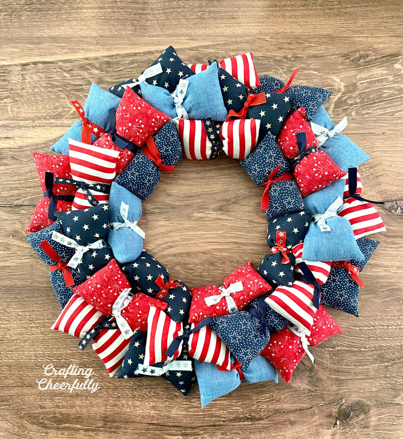 Pillow wreath made from red, white and blue fabric on a wooden background.