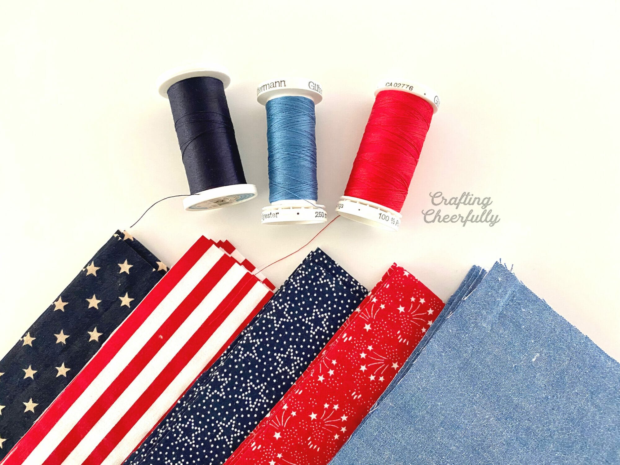 Red, white and blue fabric laying next to spools of coordinating thread.