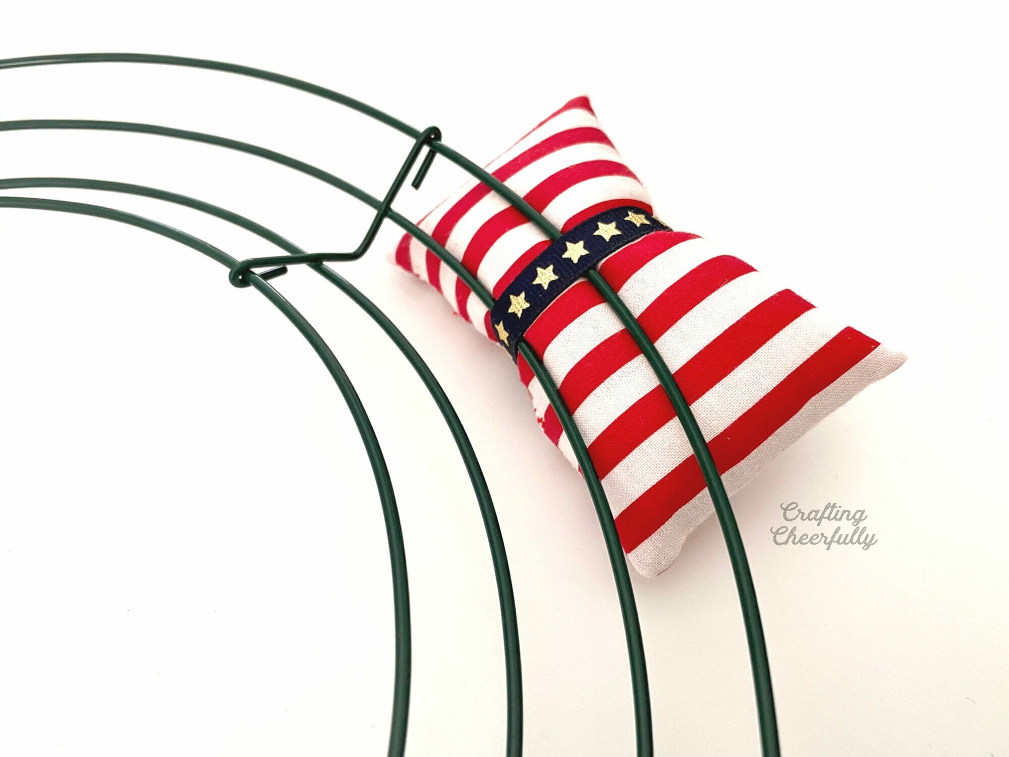 Red striped pillow tied to the metal wreath frame with blue star ribbon.