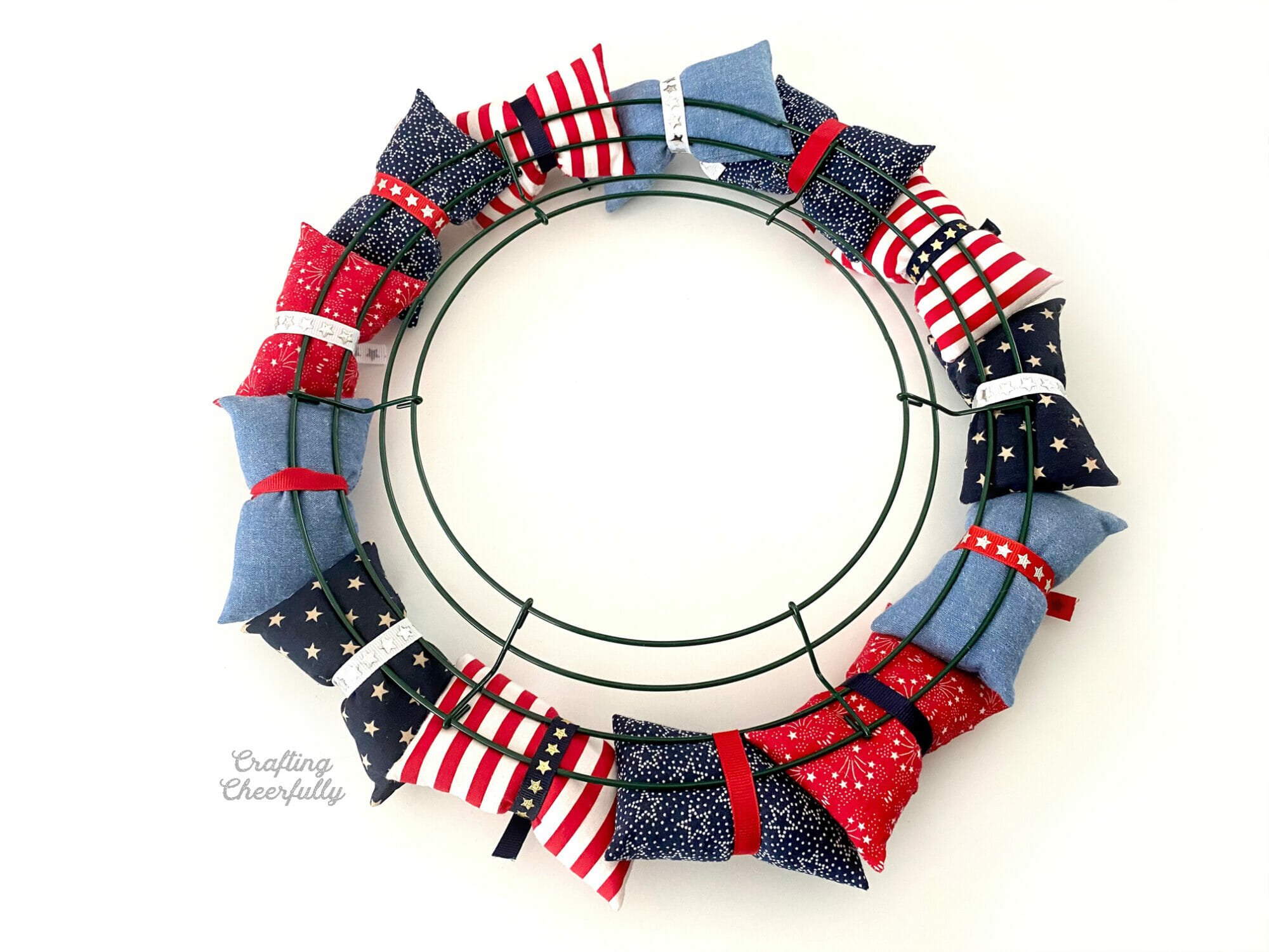 Fabric pillows tied around a wire wreath frame using ribbon.