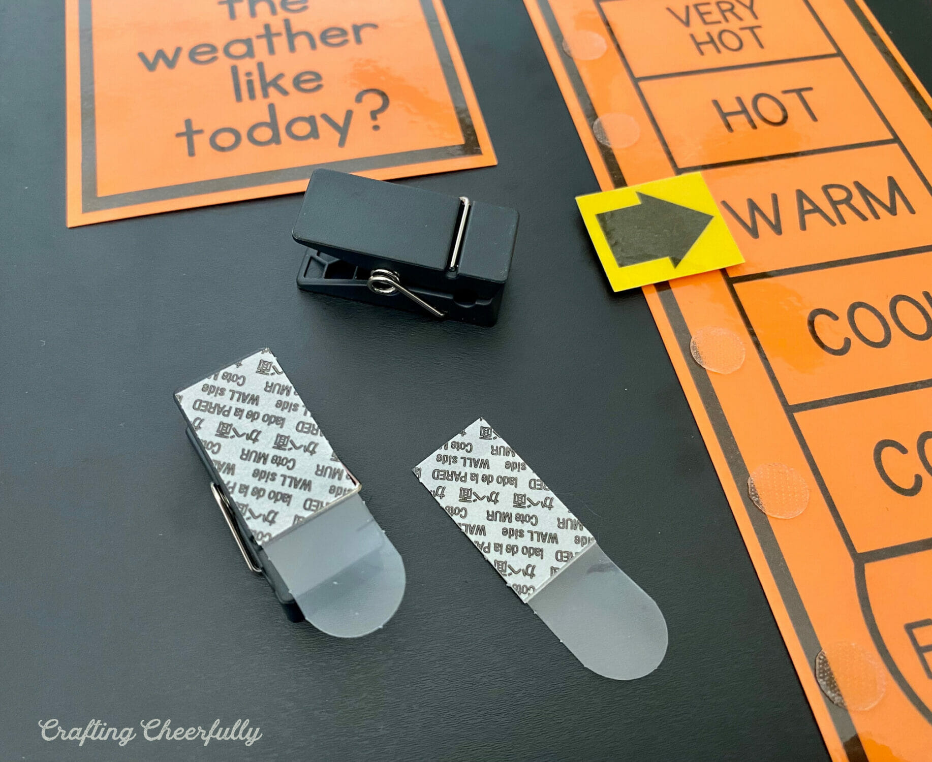 Black clips used to hold calendar printables on the chalkboard.