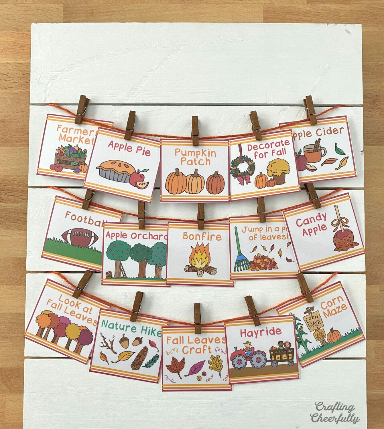 White wooden board with cards hanging from orange twine.