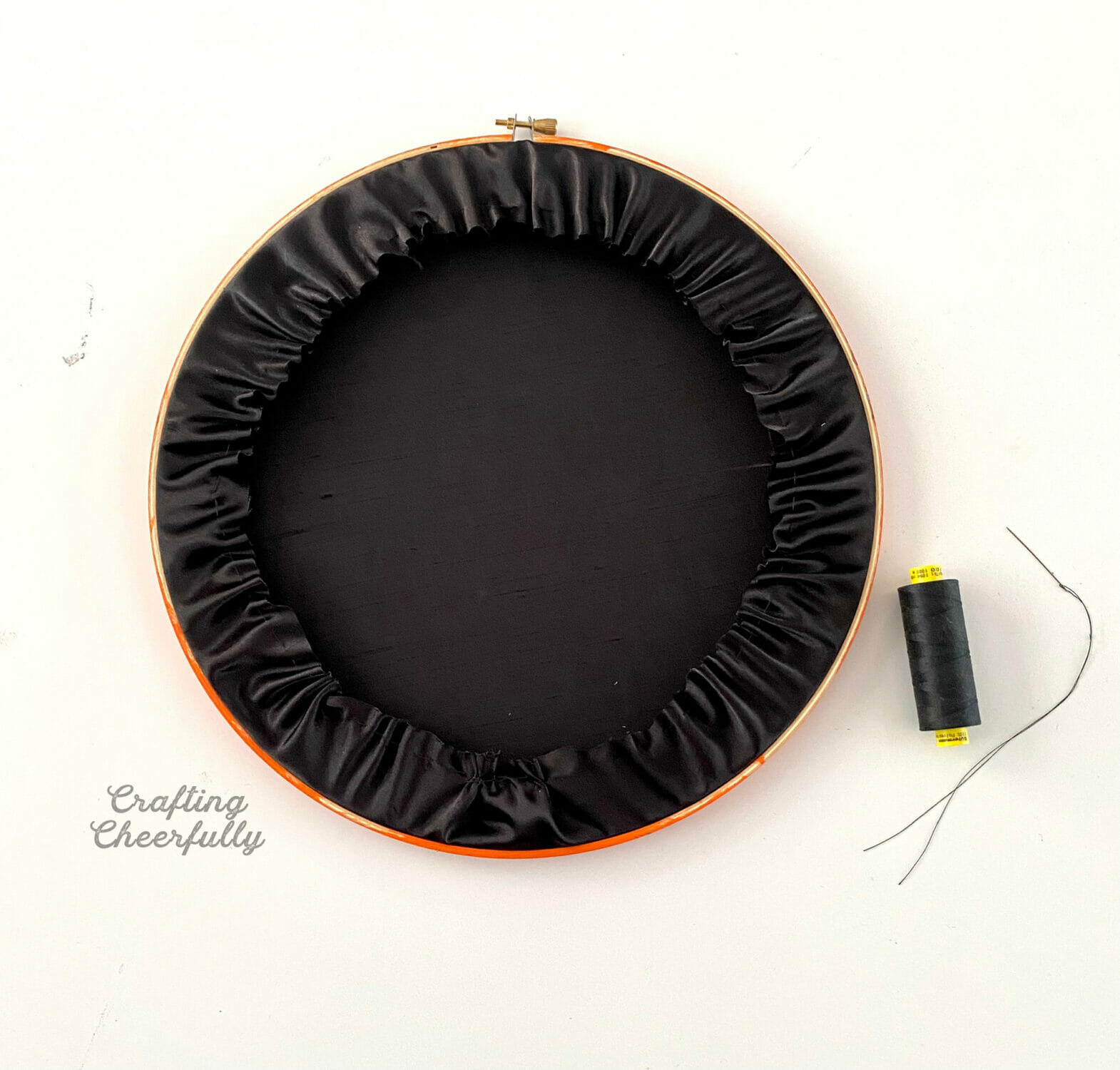 The back of the embroidery hoop showing the black fabric being gathered in.