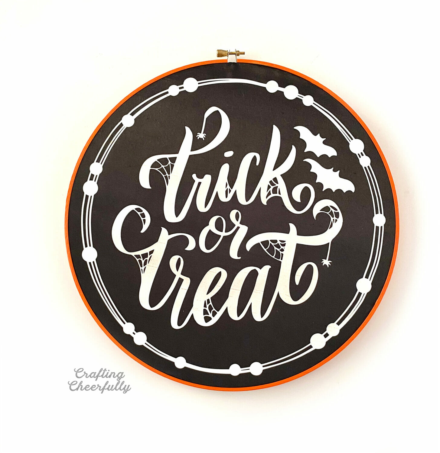 Embroidery hoop painted orange with "Trick or Treat" written in glow in the dark HTV on black fabric.