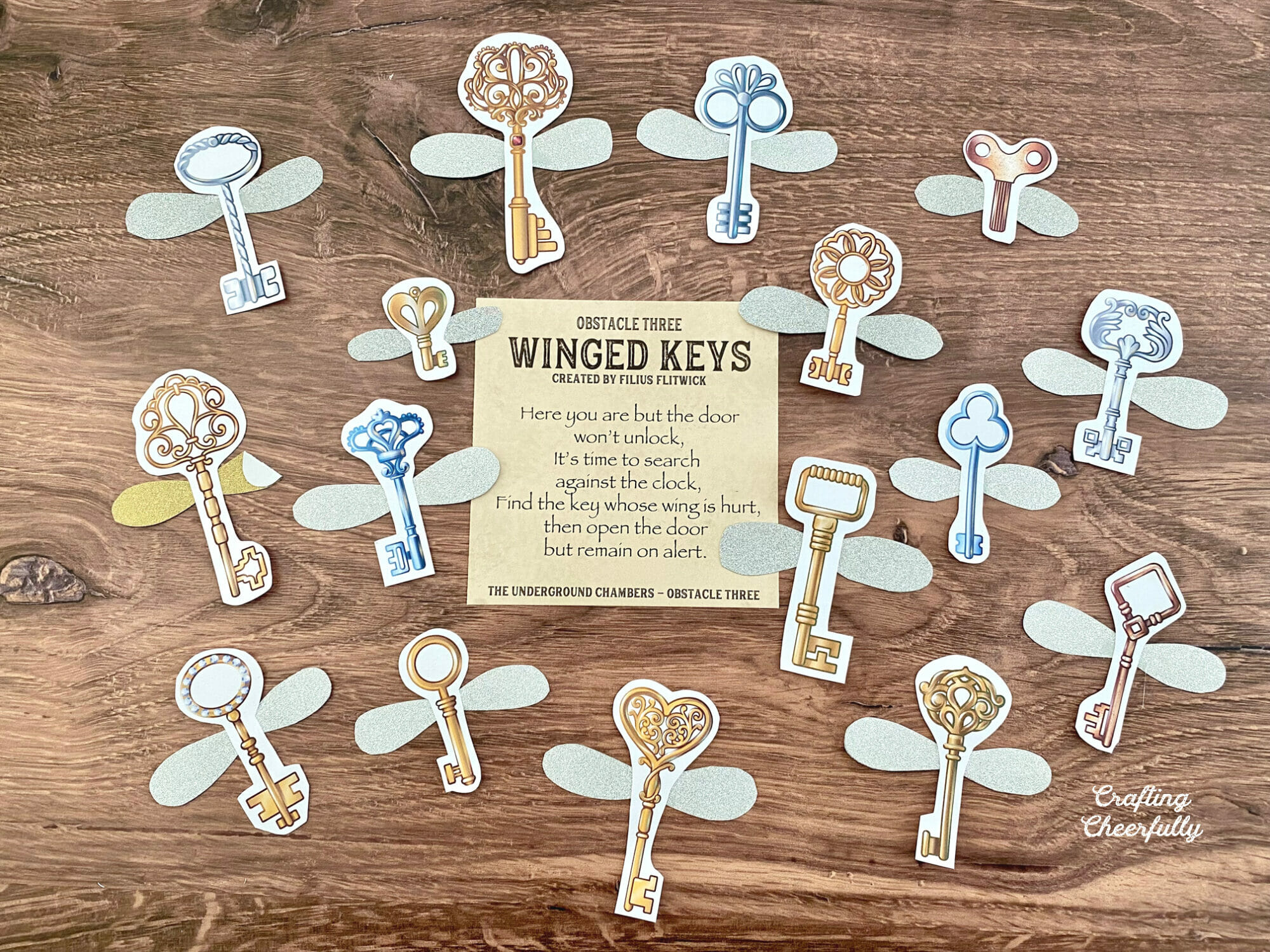 Obstacle three card lays on a table surrounded by paper keys with wings.
