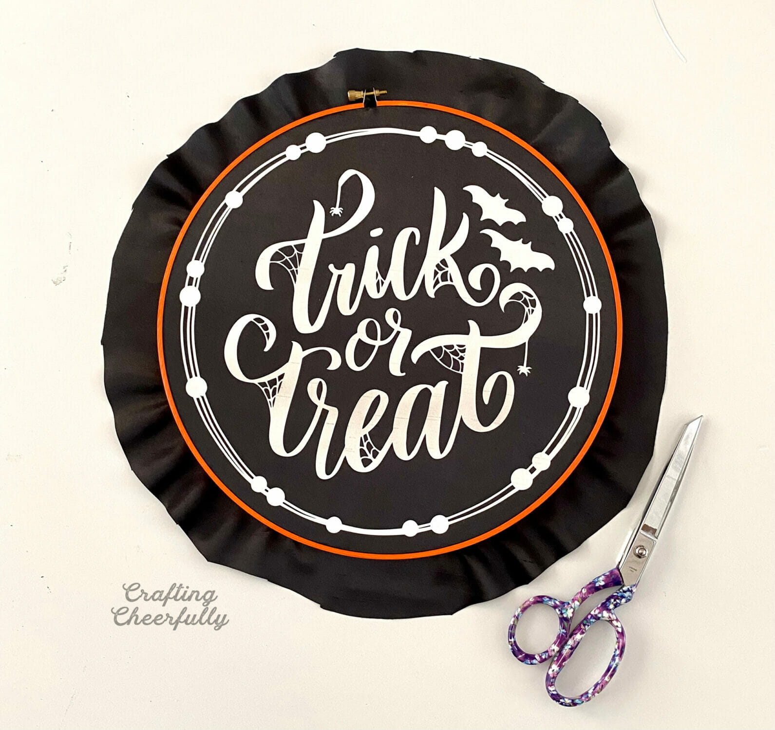 Halloween hoop with black fabric being trimmed around it.