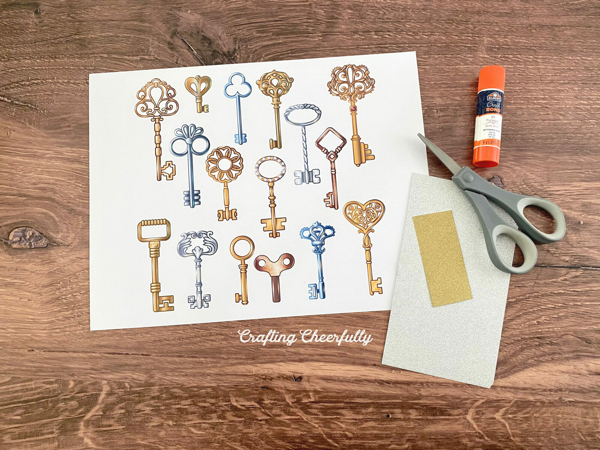 A sheet of printable keys lays next to a scissors, glue stick and glitter paper.