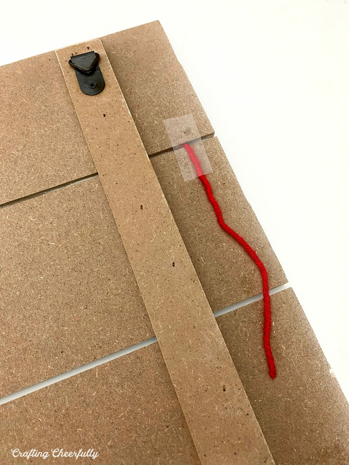 The back of the board shows red yarn held in place with clear tape.