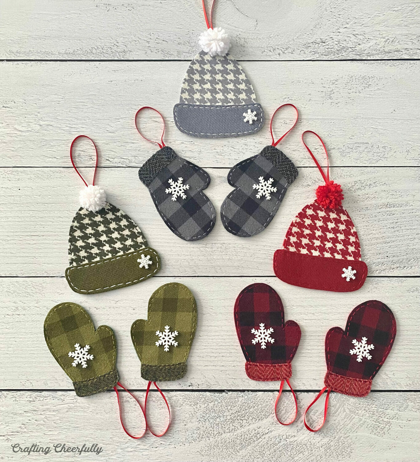 Cozy winter ornaments including mittens and winter hats lay on a white wooden table.