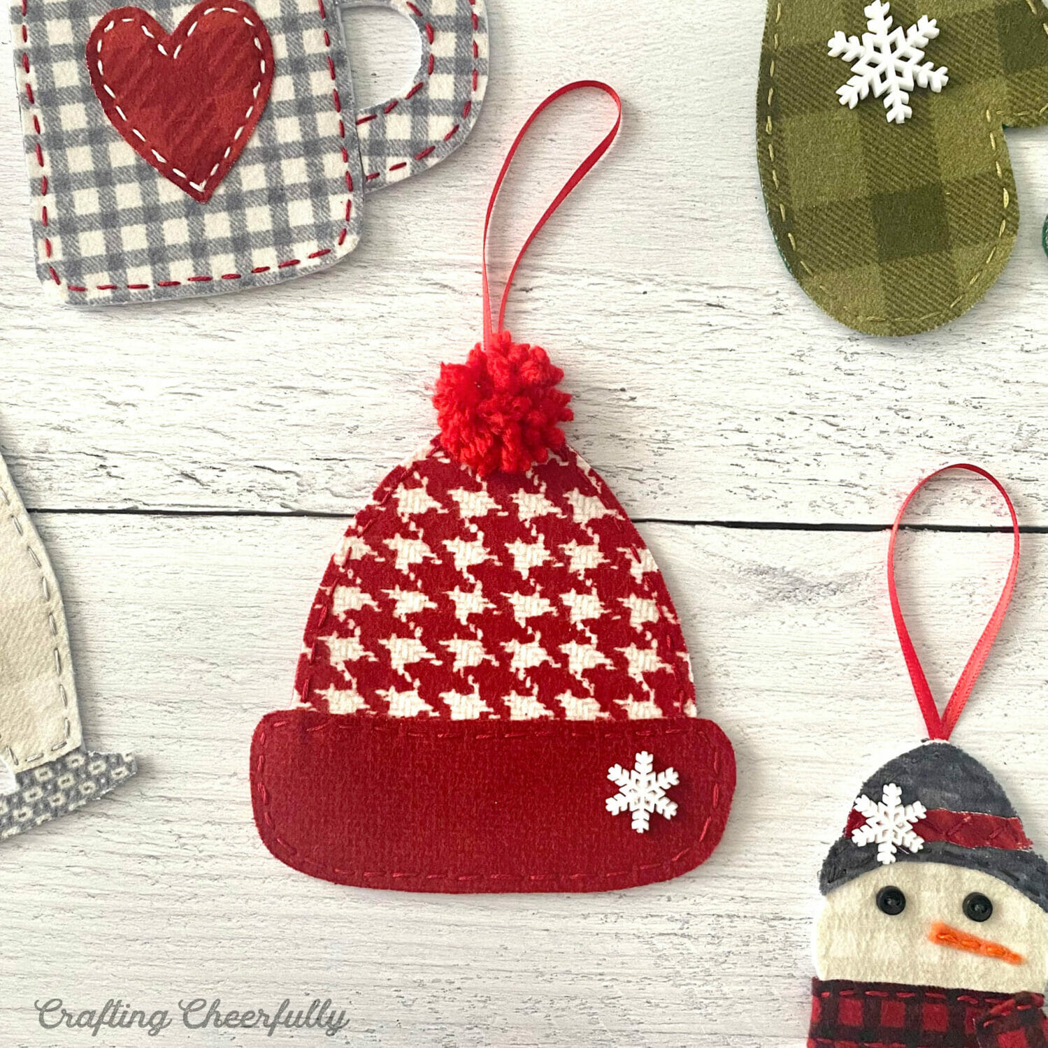 A red fabric ornament with as snowflake button on the brim and a red Pom Pom on top.