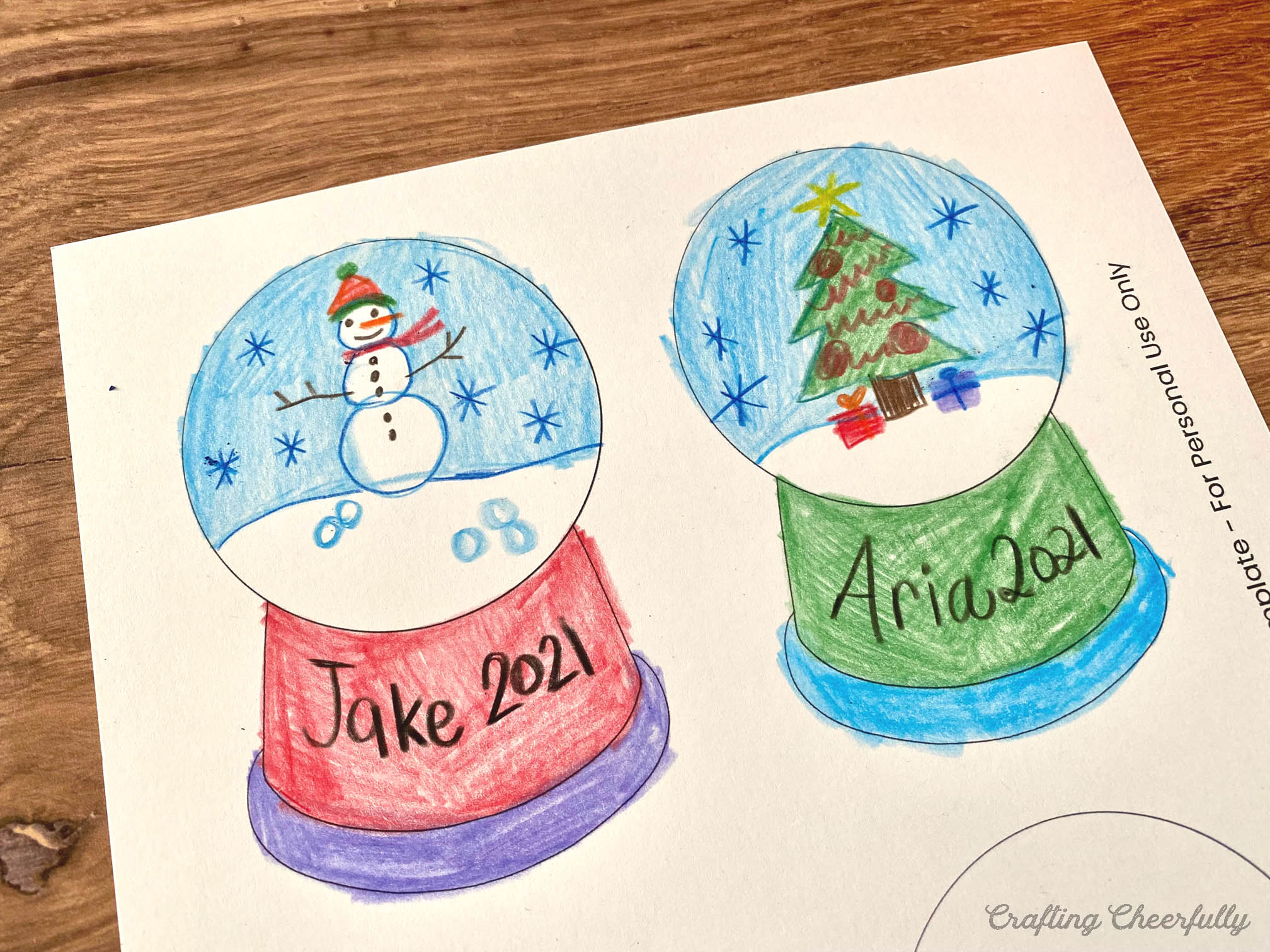 The snow globe ornament template is colored in with a child's name and the year written on the base.