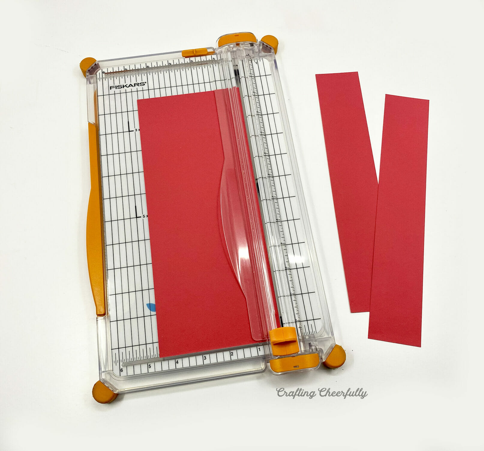 Strips of red pacer being cut with a paper trimmer.