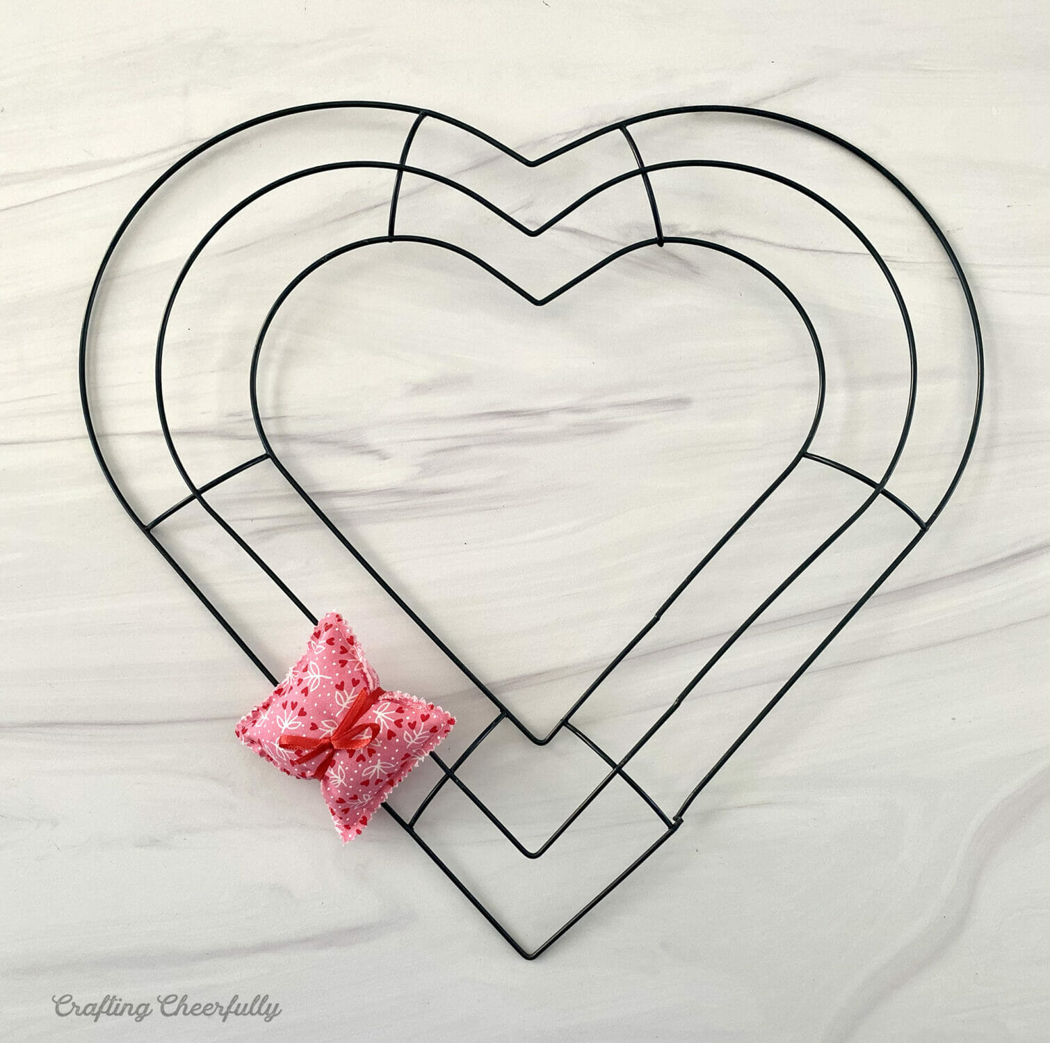 One pillow is tied to a heart wreath form using ribbon.