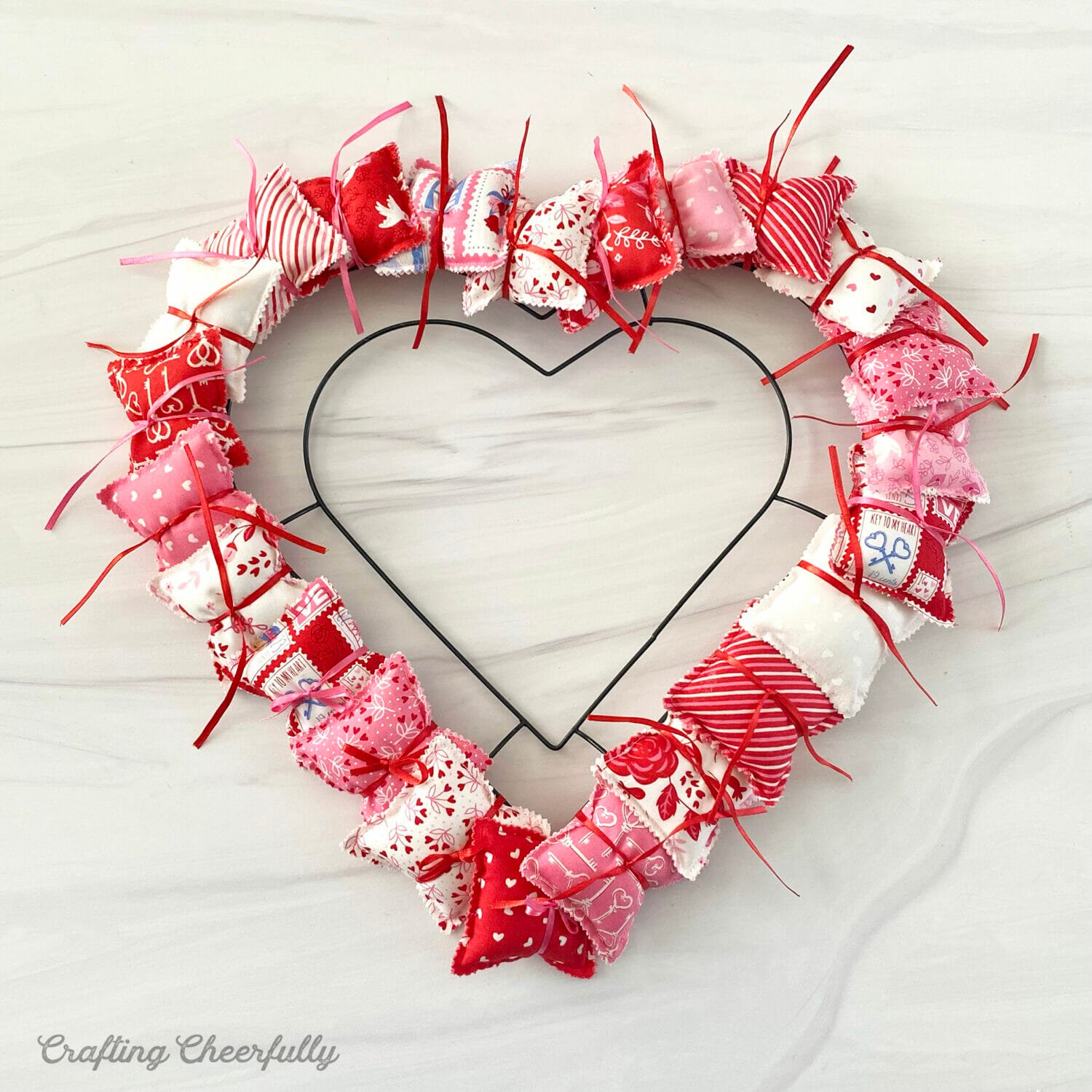 Tiny fabric pillows are tied onto the heart wreath form.
