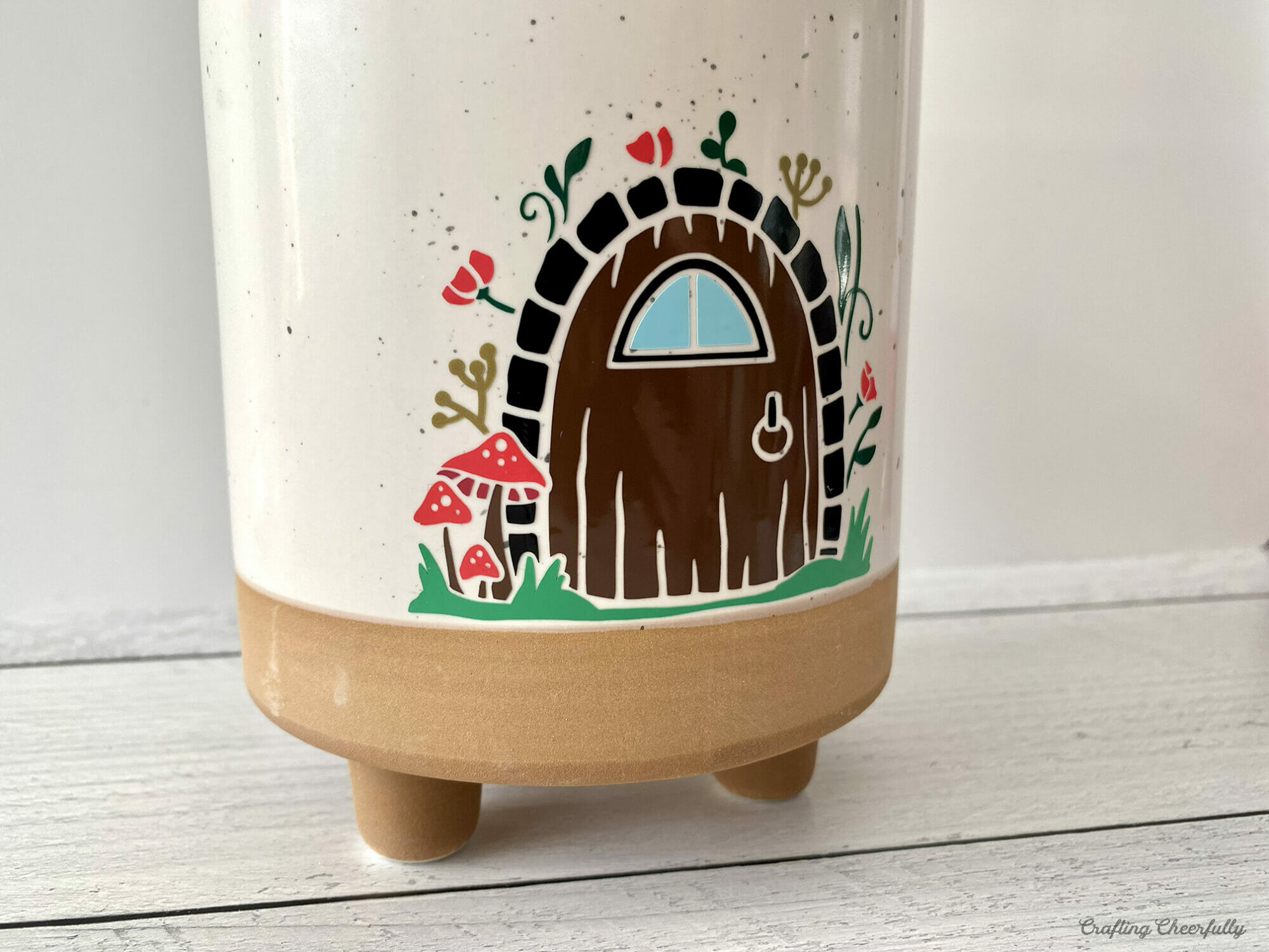 White flower pot with colorful fairy door cut from vinyl.