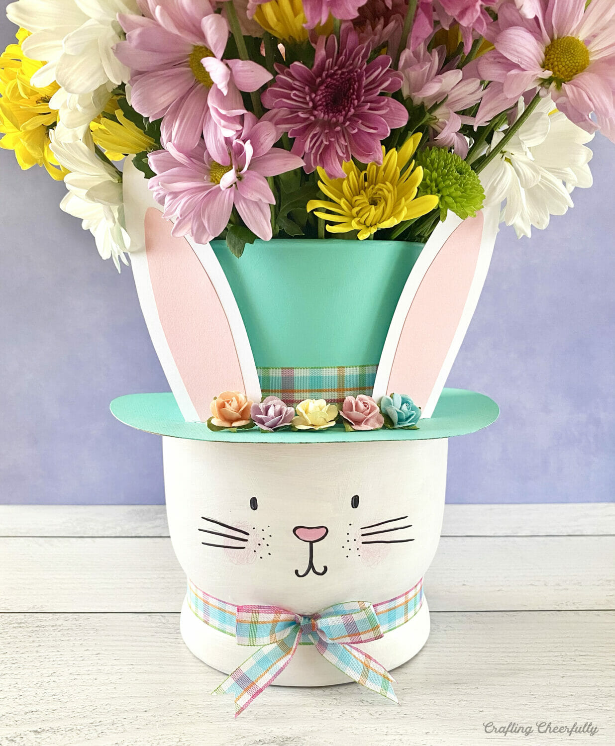 Easter bunny vase with flowers coming out of a teal top hat.