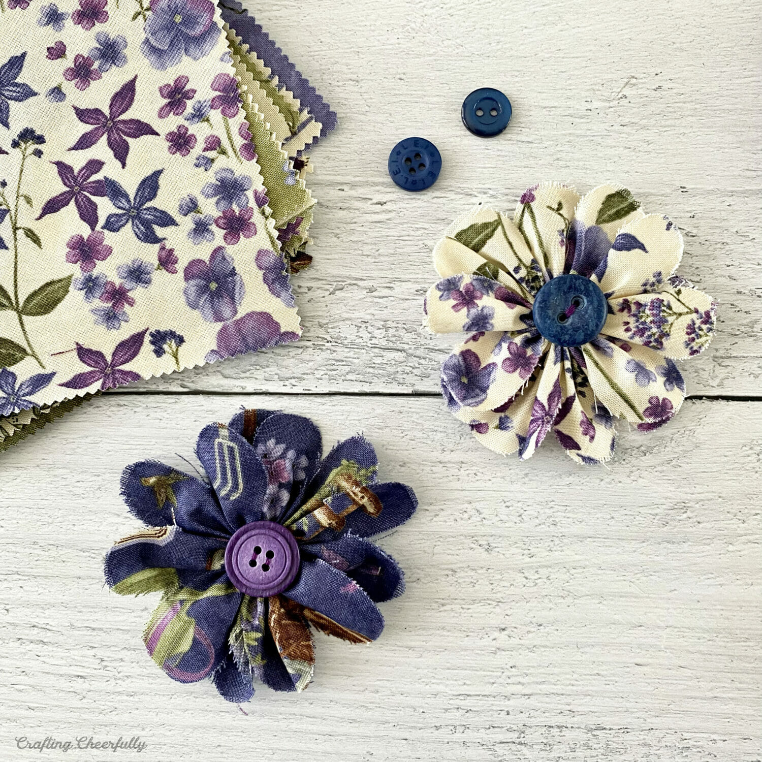 Fabric flowers with buttons and a fabric charm pack.