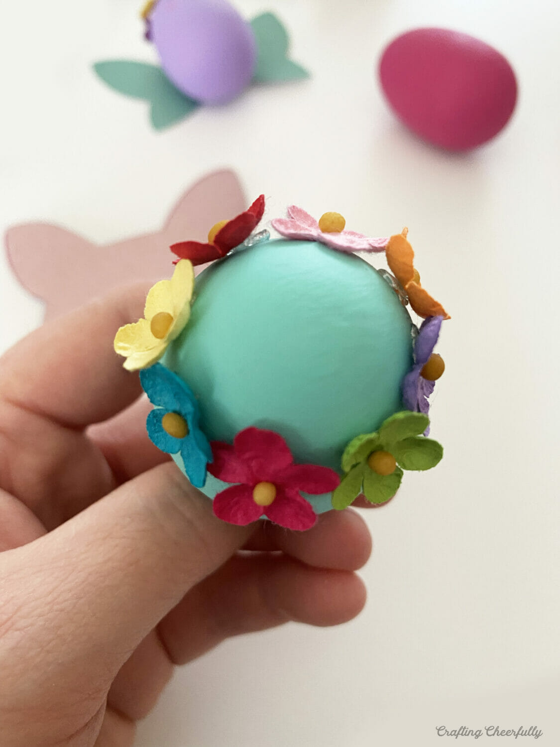 Cute paper flowers are attached around the top of the Easter egg.