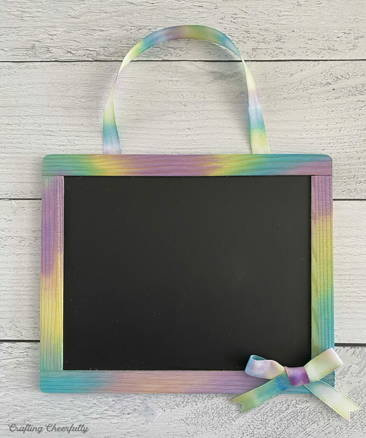 Tie dye ribbon is added to the chalkboard as a handle a bow accent in the lower right corner.