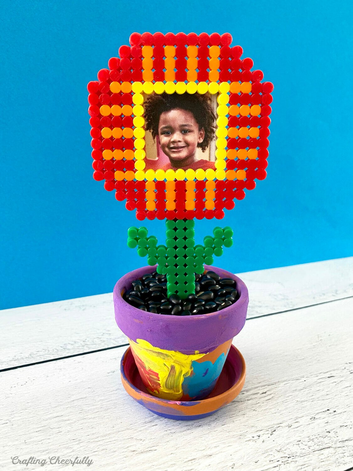 A perler bead flower frame with a child's photo in it.