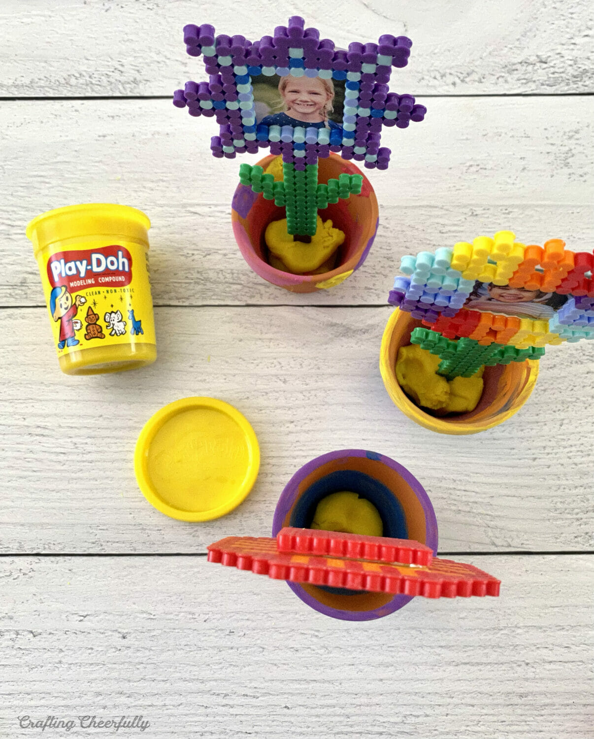 Yellow playdough is squished into the bottom of the flower pots.