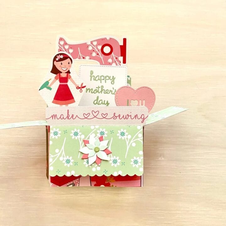Pop up sewing card with a woman holding a glue gun and a sewing machine behind her.