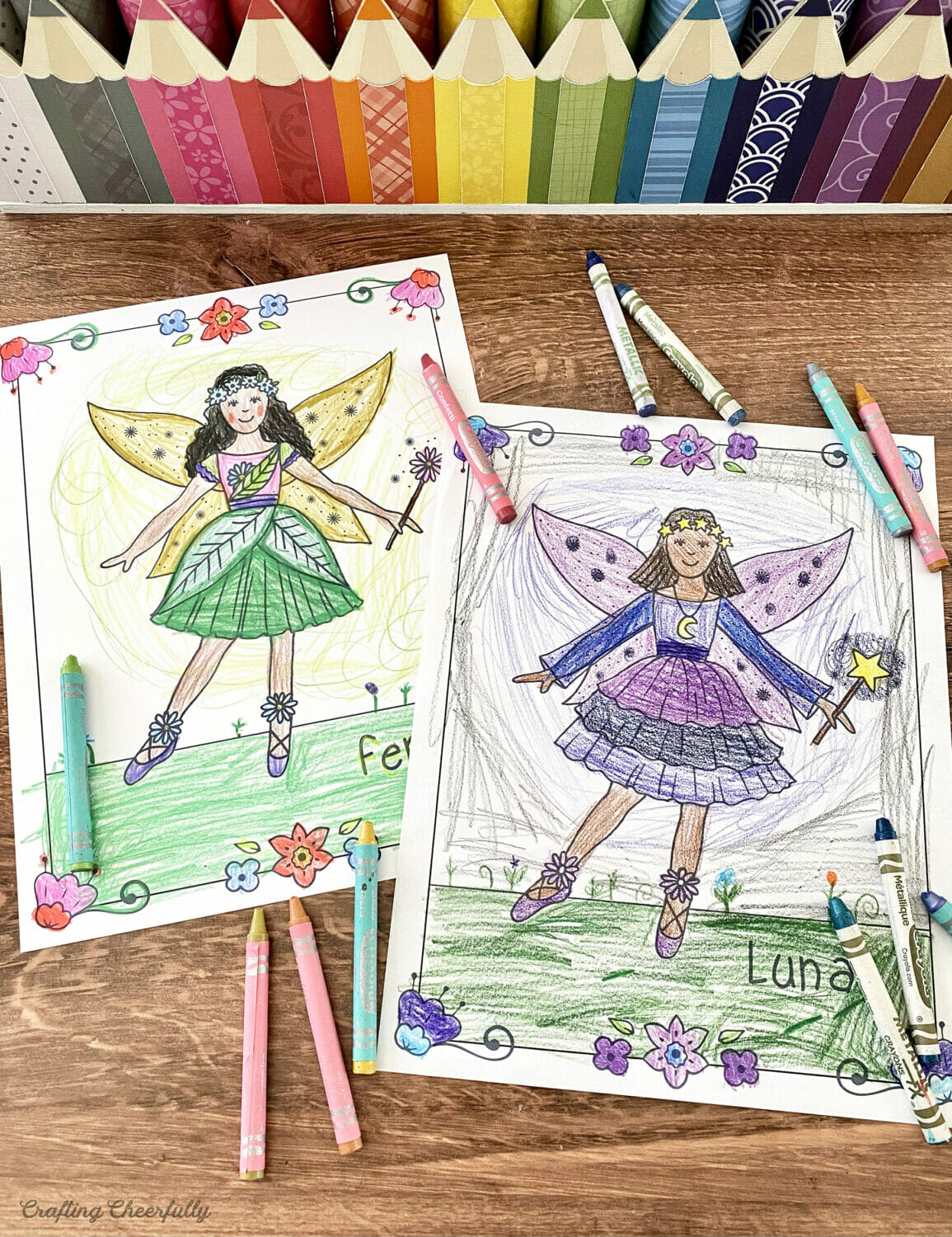 Fairy coloring pages colored by a child lay on a table with crayons.