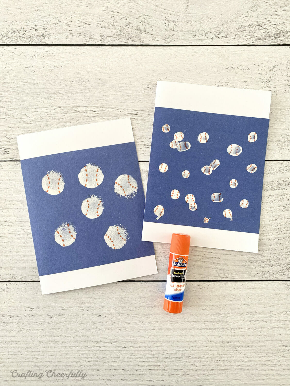 Blue construction paper with baseballs on them glued to white cardstock.