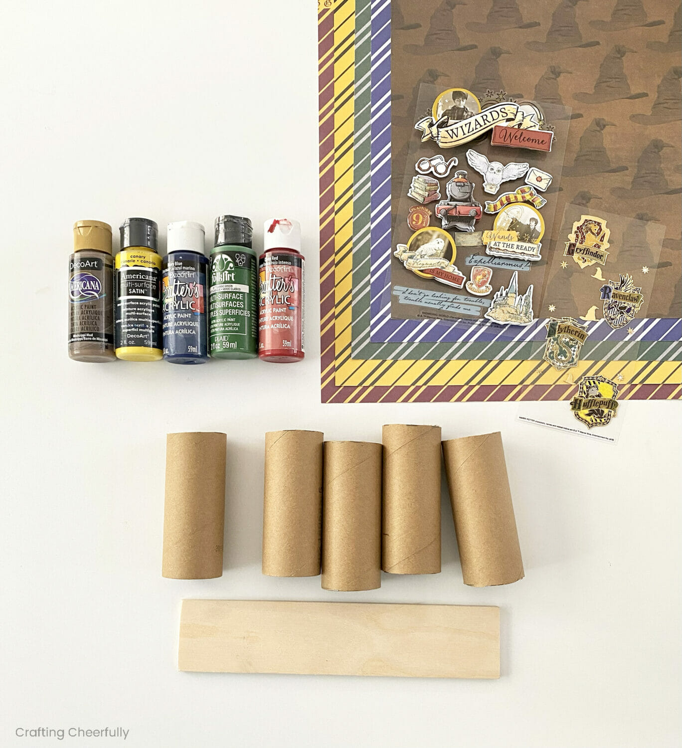 Cardboard tubes, Harry Potter-themed scrapbook paper and stickers, and acrylic paint bottles.