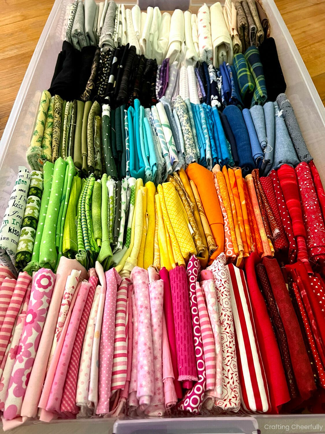 Fabric sorted by color in an under the bed bin.