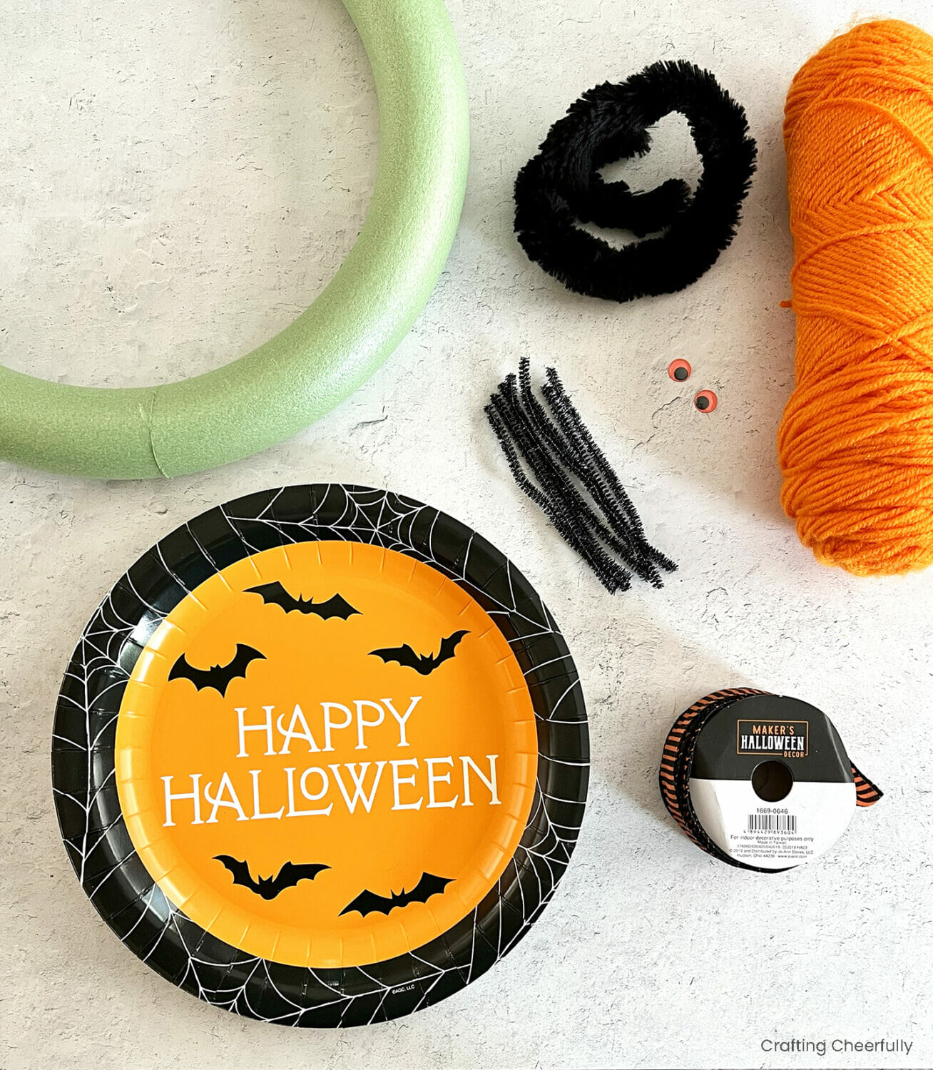 Foam wreath form, Halloween paper plate, black pipe cleaners, ribbon and a roll of orange yarn.