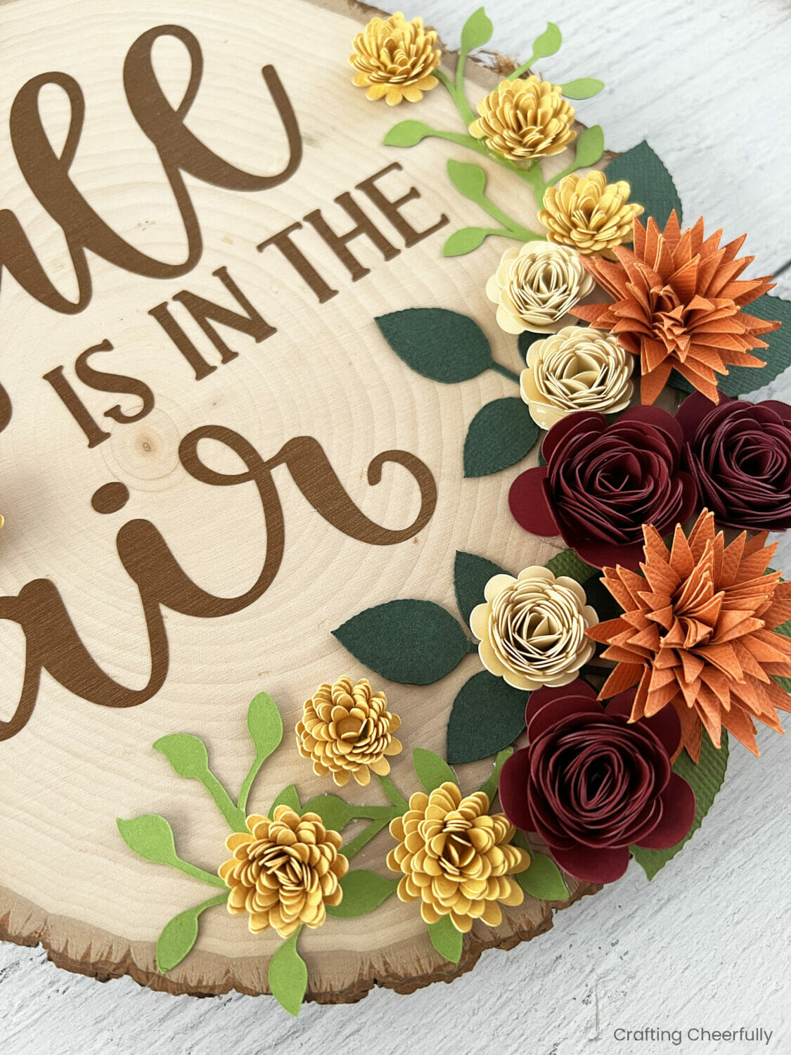 Paper flowers along the bottom of a wood slice.