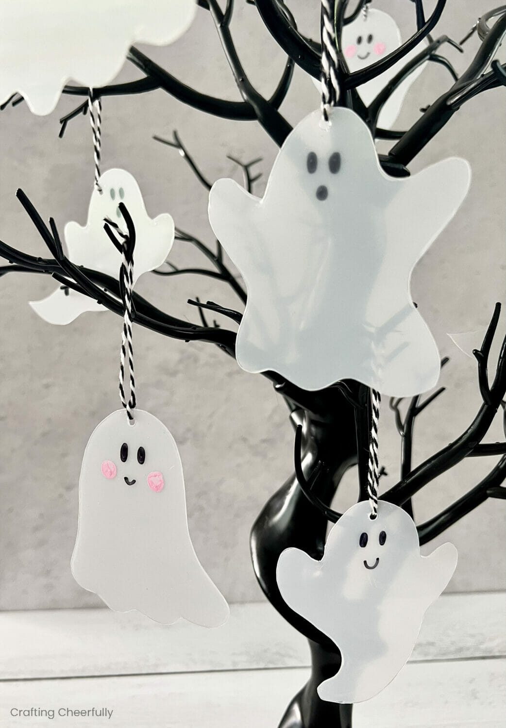 Ghost Halloween ornaments hang from a spooky black tree.