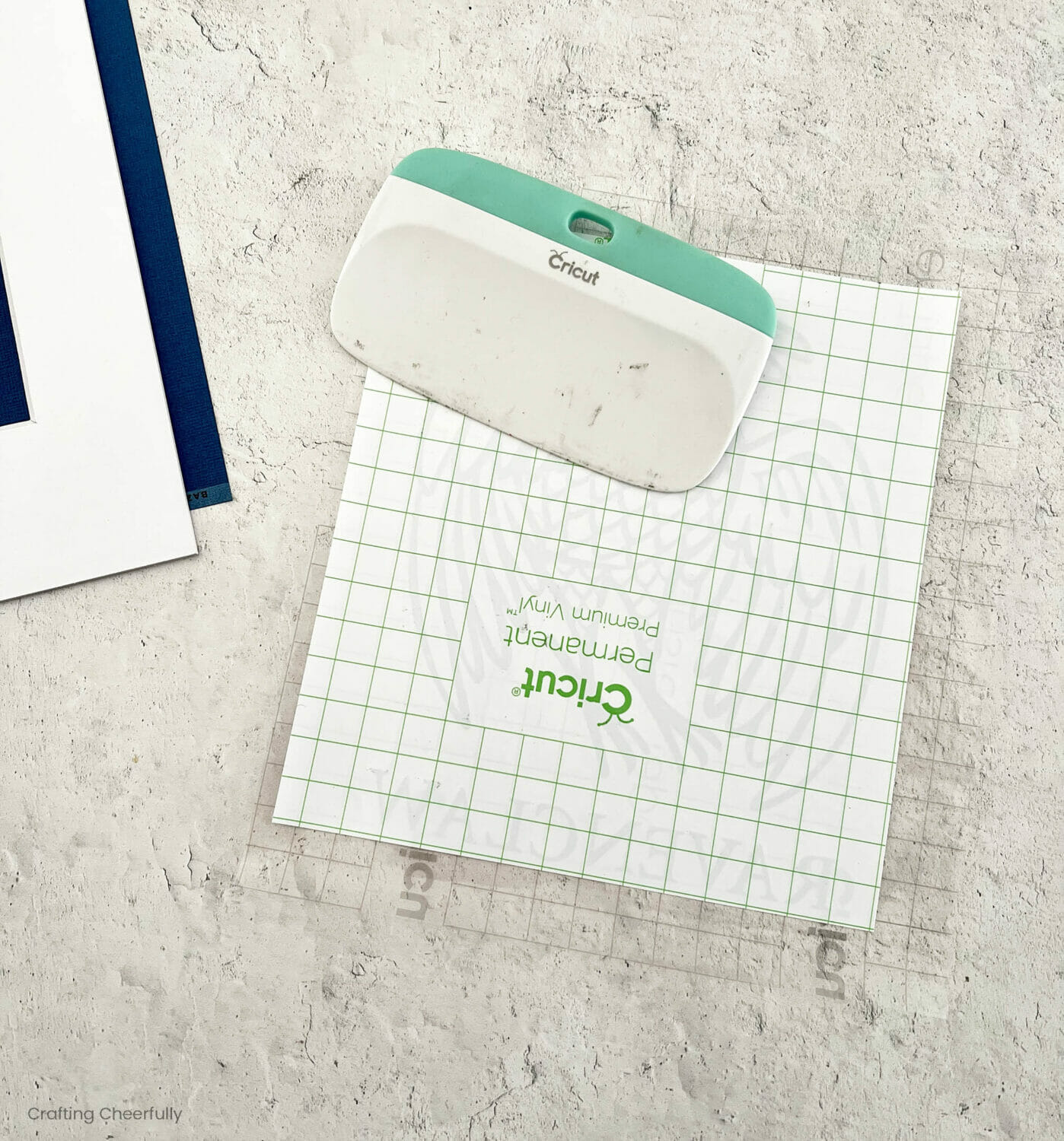 A scraper lays on top of an image covered in transfer tape.