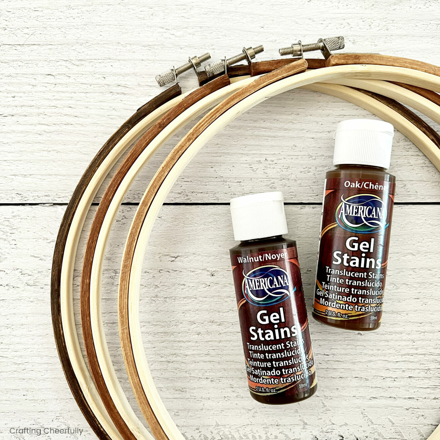 Two bottles of Deco Art Gel Stain lay inside embroidery hoops.