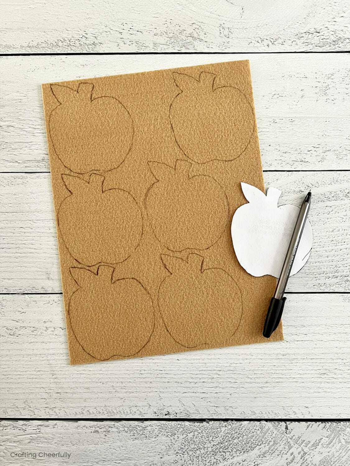 Apple template is laid over a piece of tan felt and traced.