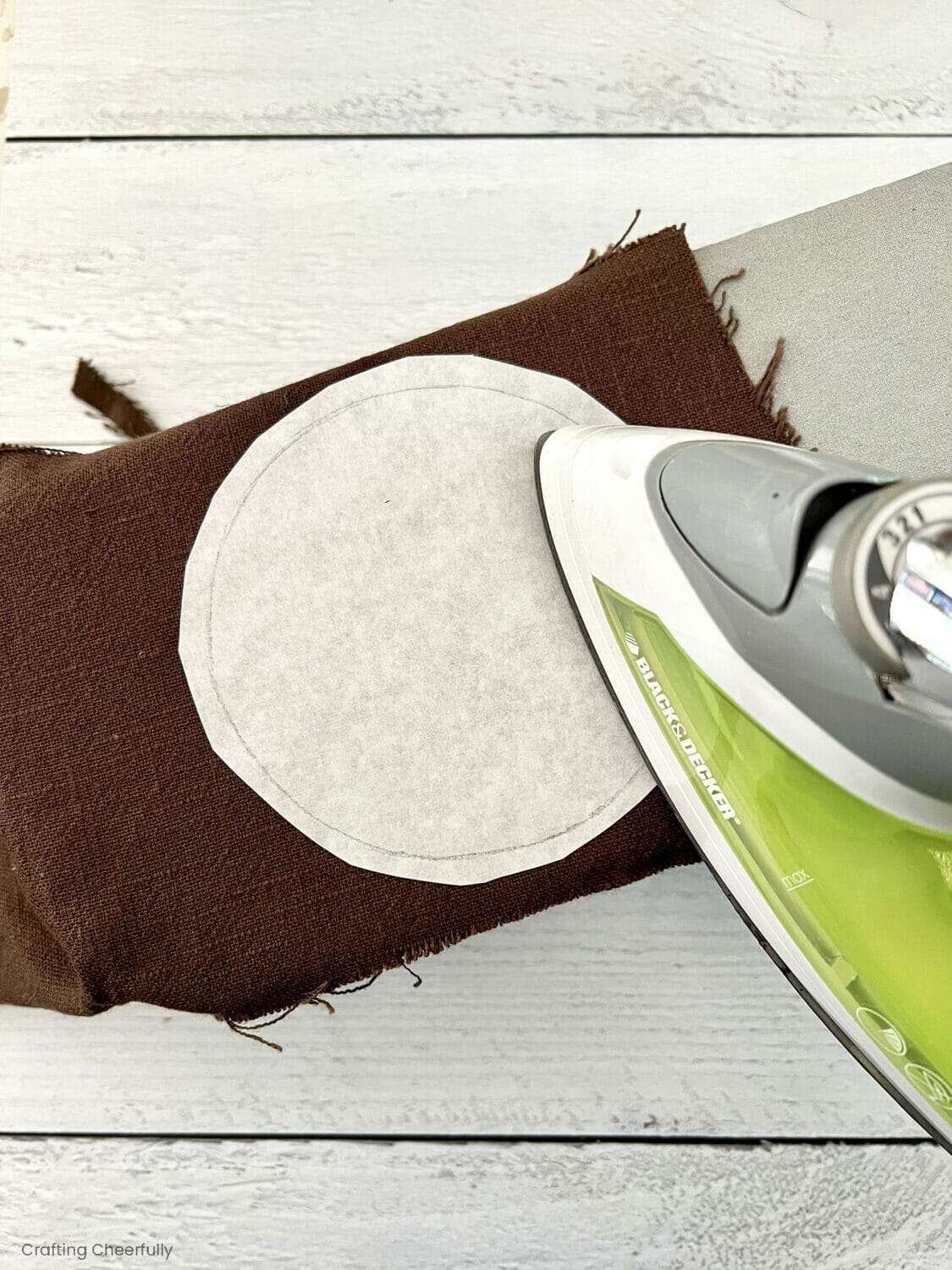 An interfacing circle is ironed onto brown fabric. 