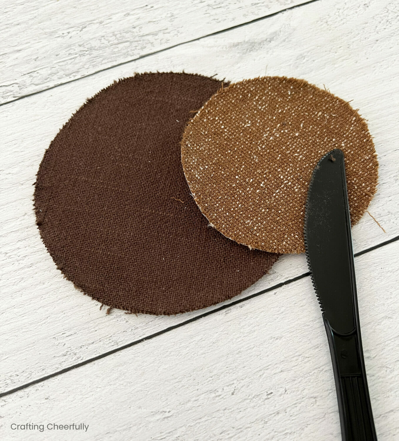 Two circles of brown fabric lay next to a plastic knife.