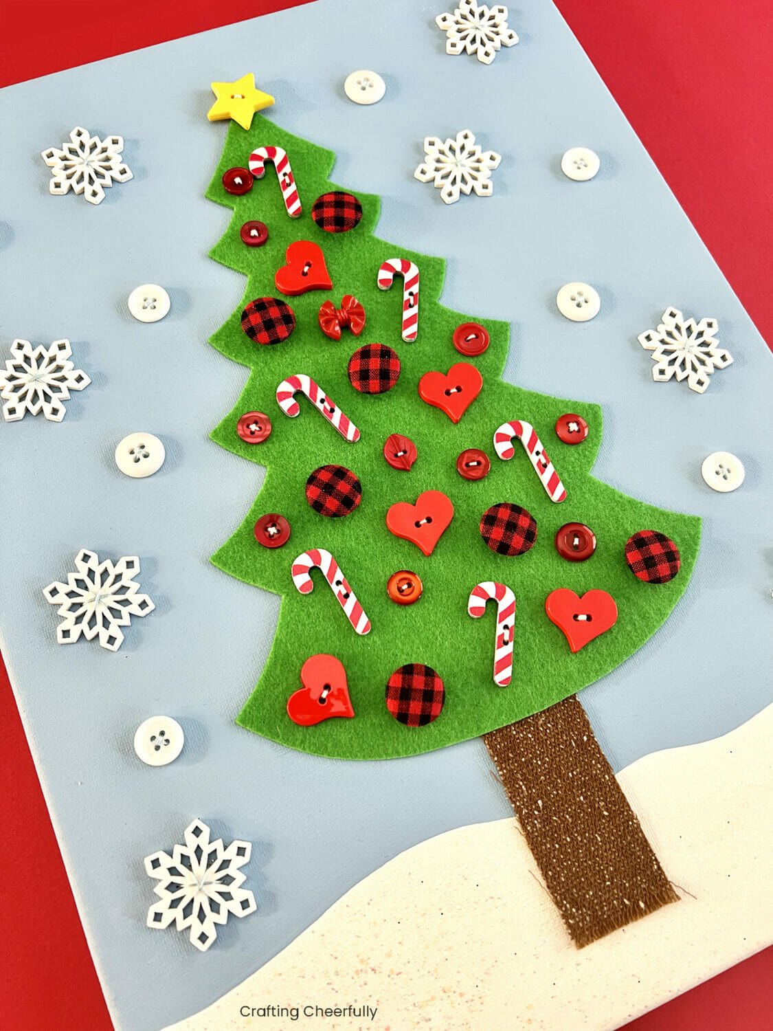 Christmas tree decorated with buttons on a piece of holiday canvas art.