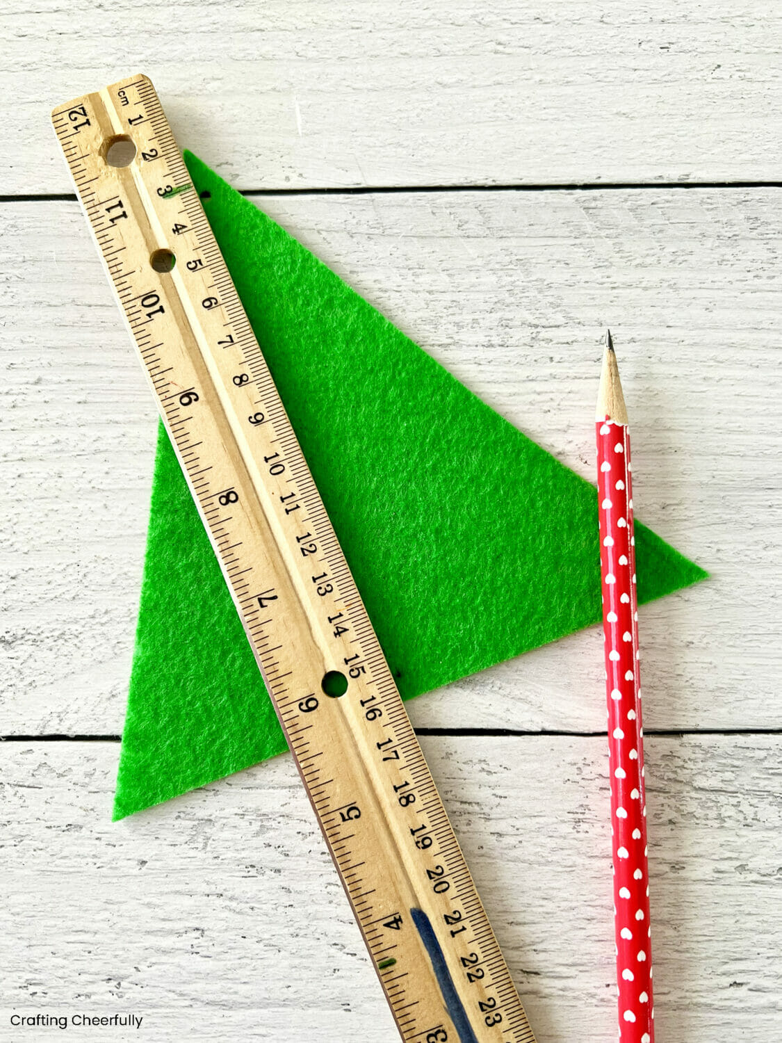 A ruler is used to mark where to punch holes at the top and bottom of the green triangle.