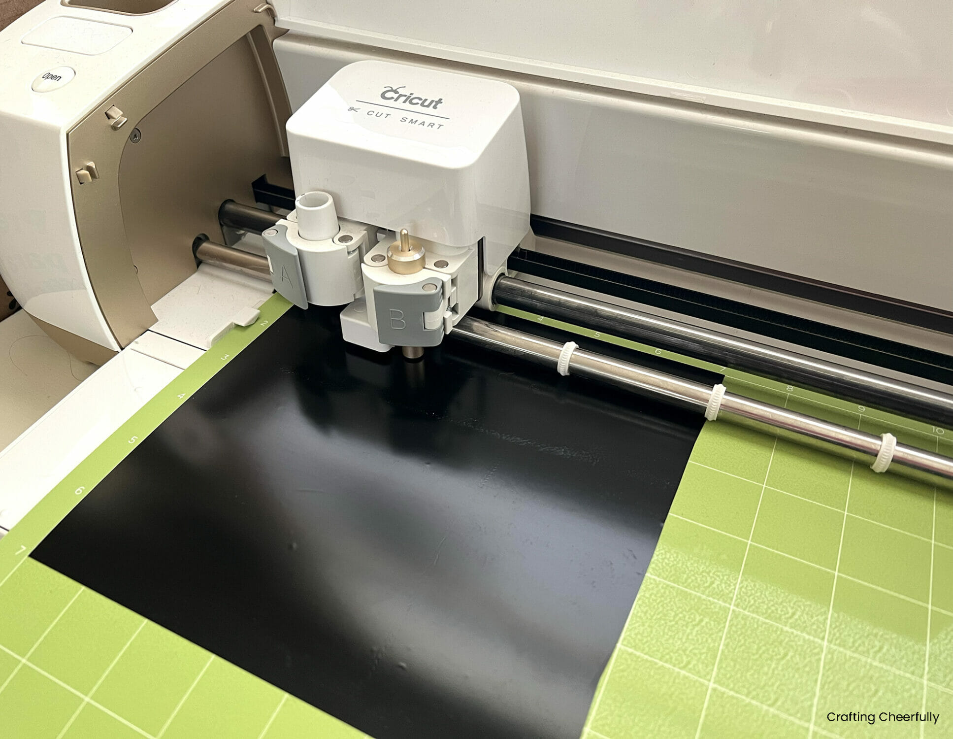 A cricut cutting machine cuts a piece of black vinyl.