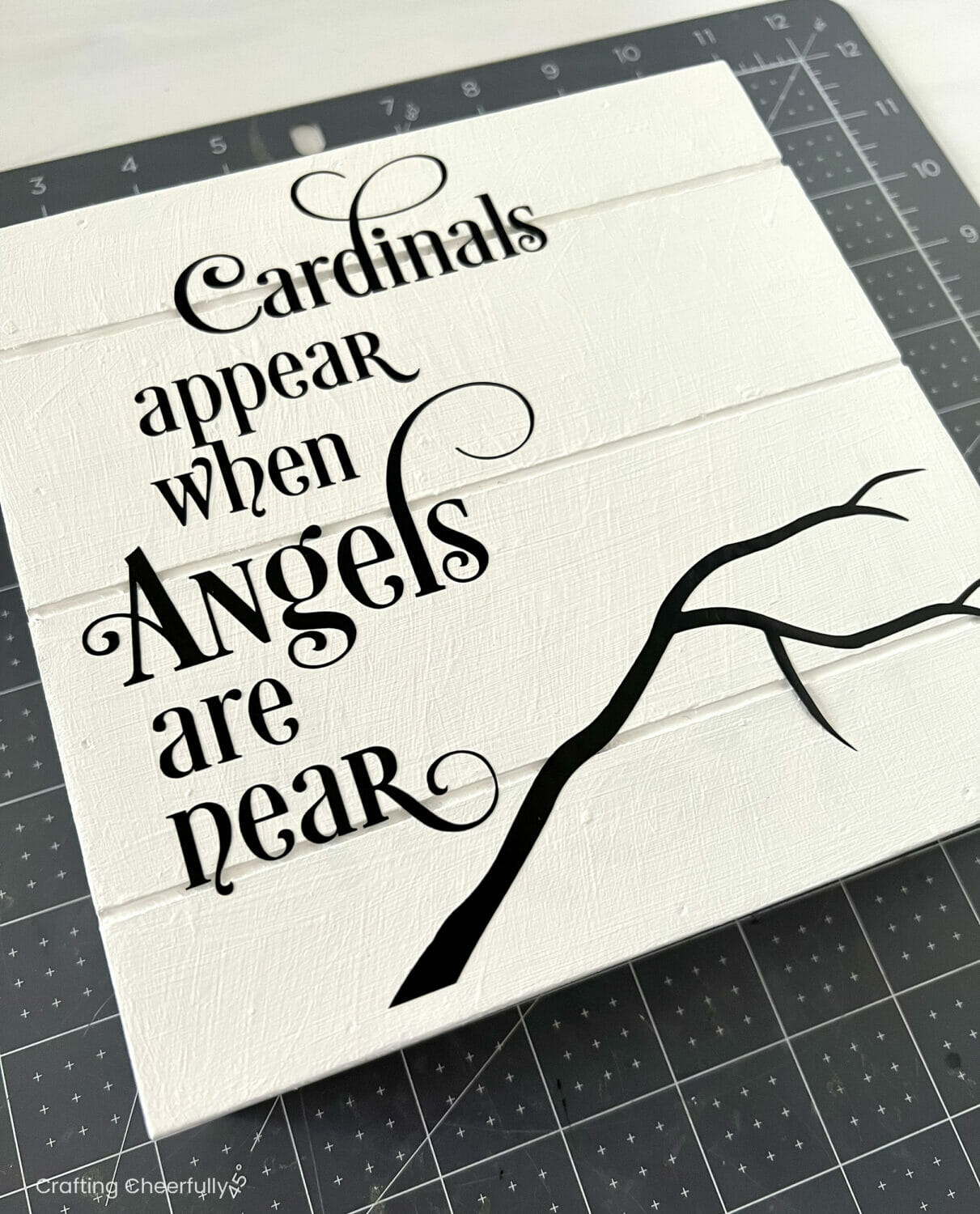 Black vinyl design applied to the white wooden sign; design reads "Cardinals appear when angels are neat" with a black branch at the bottom.