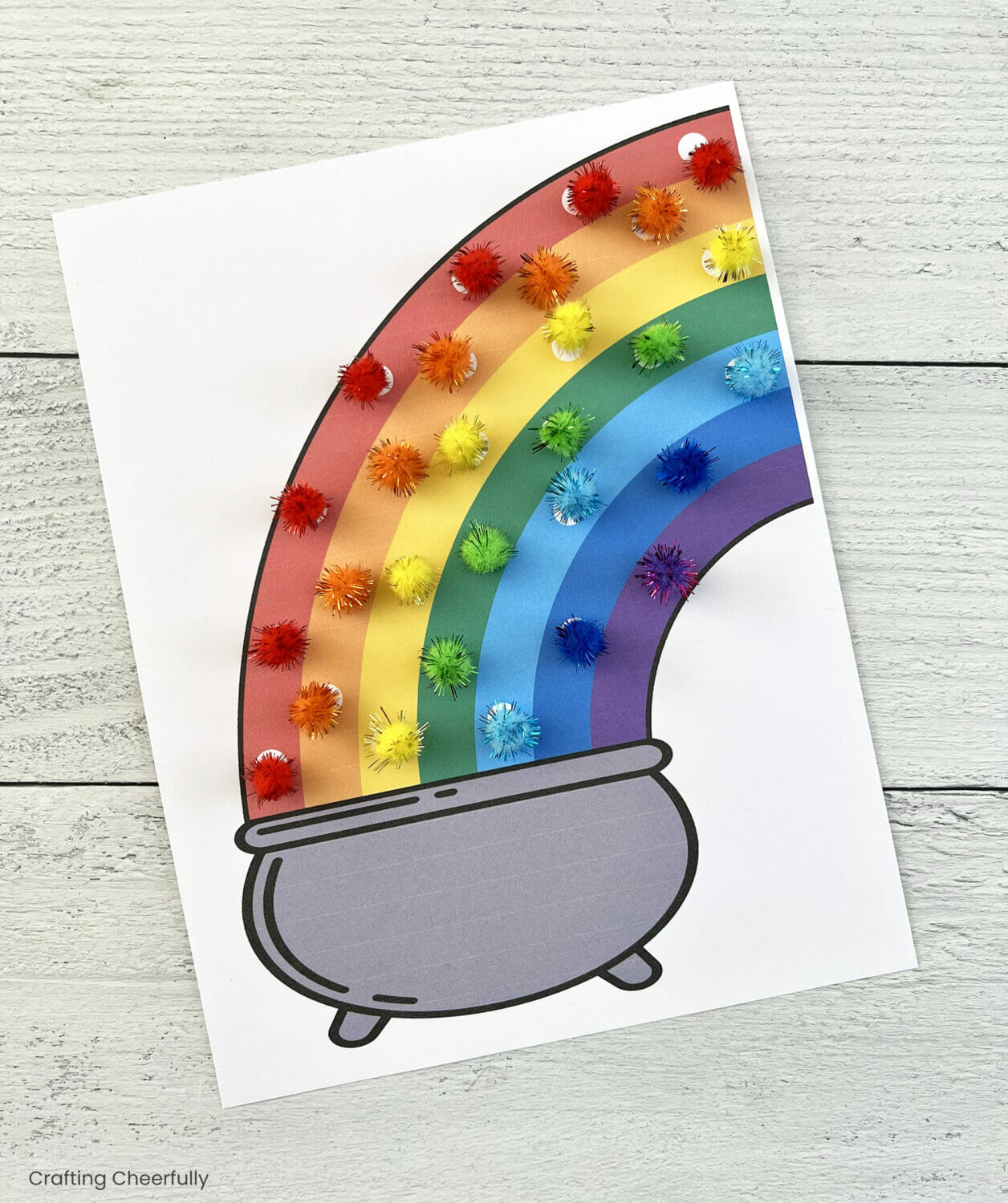 A rainbow worksheet with rainbow pompoms placed following the colors.